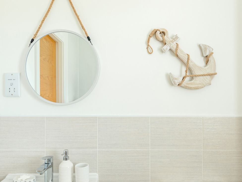 A bathroom with a mirror and anchor decoration at Wee Jules By The Sea