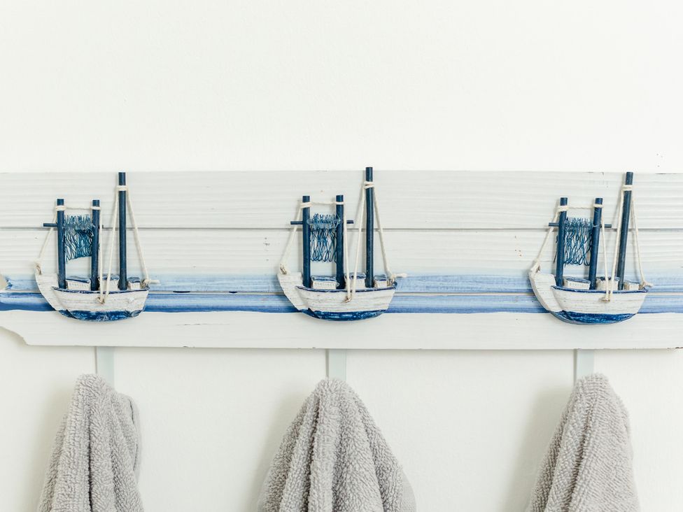 A wall with boat decorations and towels hanging at Wee Jules By The Sea