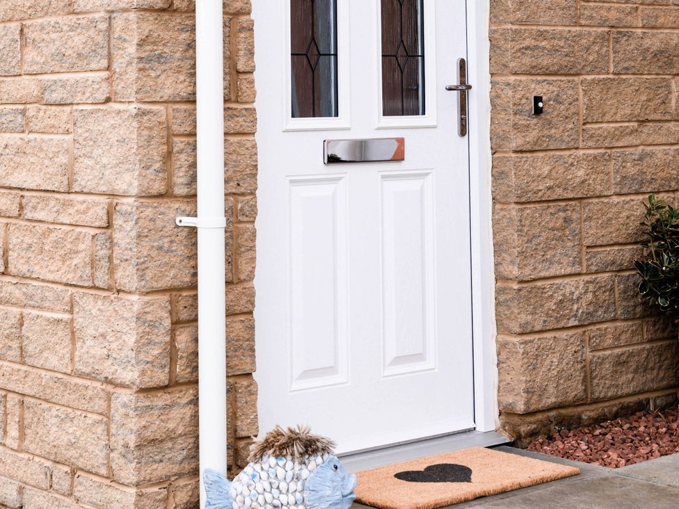 A front door with a fish-shaped decoration and a doormat at the entrance