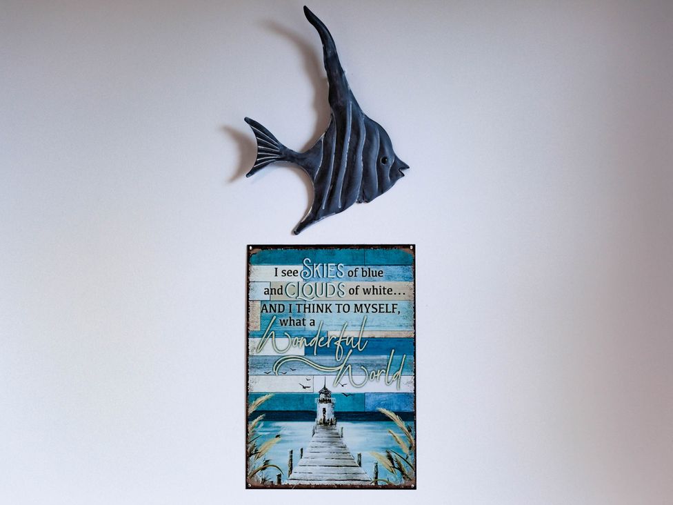 A fish decoration and a wall sign with a quote at an unspecified location
