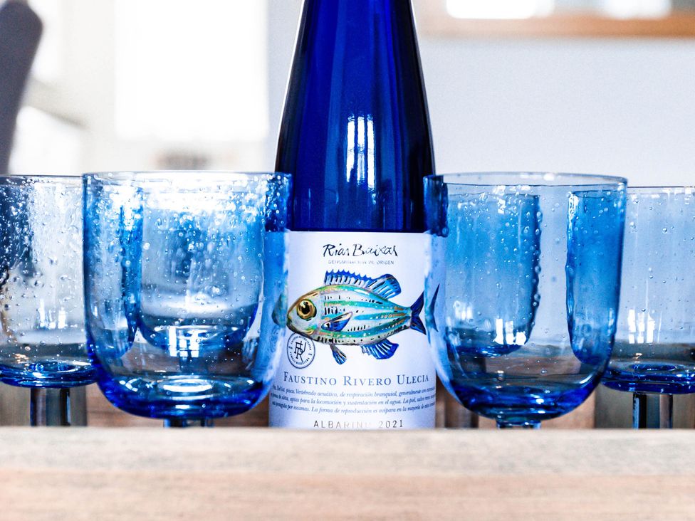 A wine bottle and blue glasses on a table at 