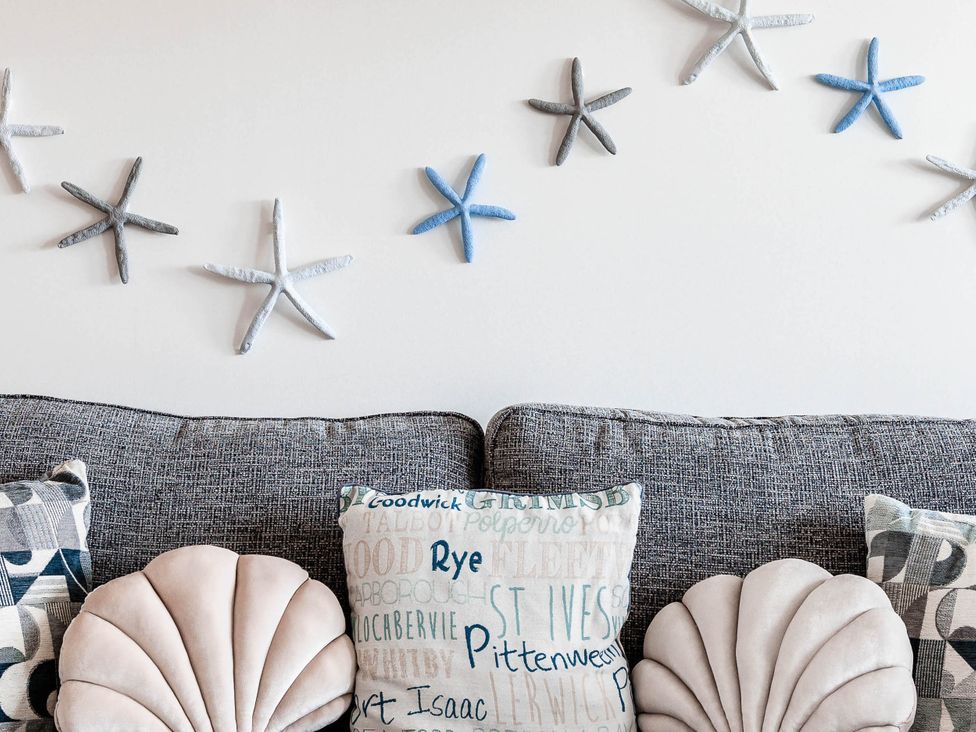 A living room with starfish decorations and cushions on a sofa at The Old Barn in Manchester
