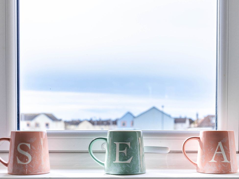 Three cups on a windowsill with a view at the kitchen