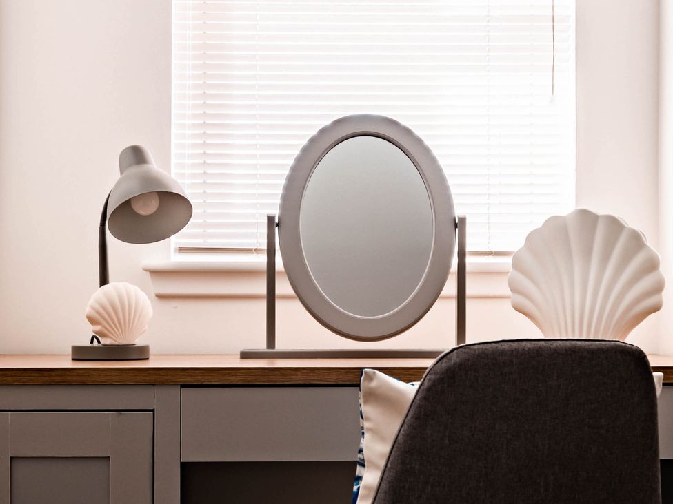 A desk with a mirror, lamp, and decorative shell at a modern interior