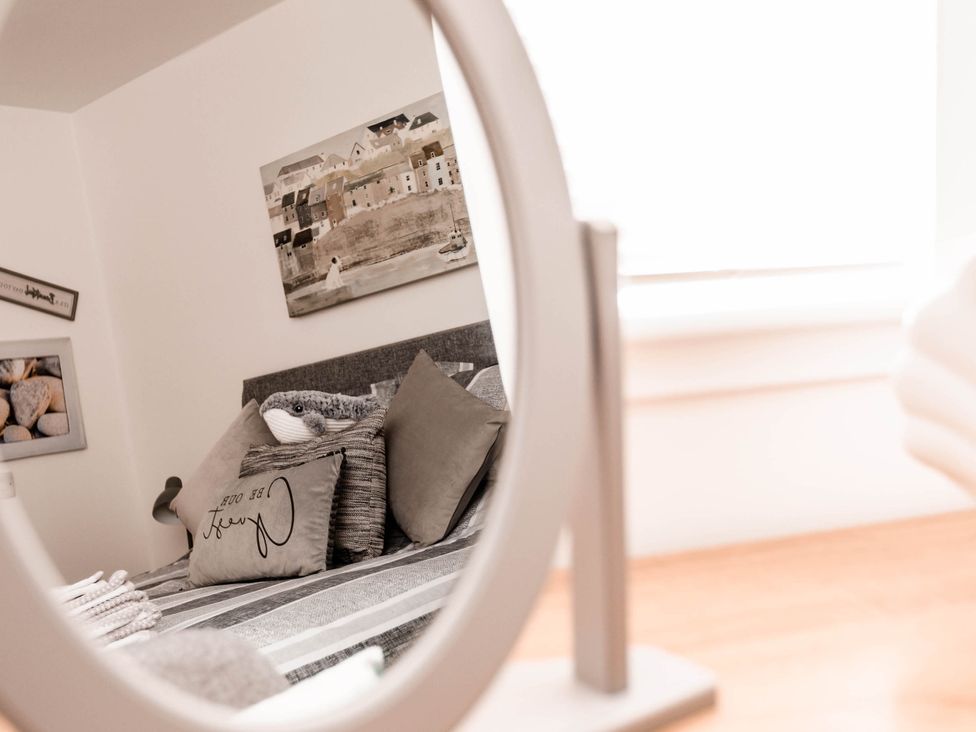A bedroom with a bed and pillows visible in a mirror at the property