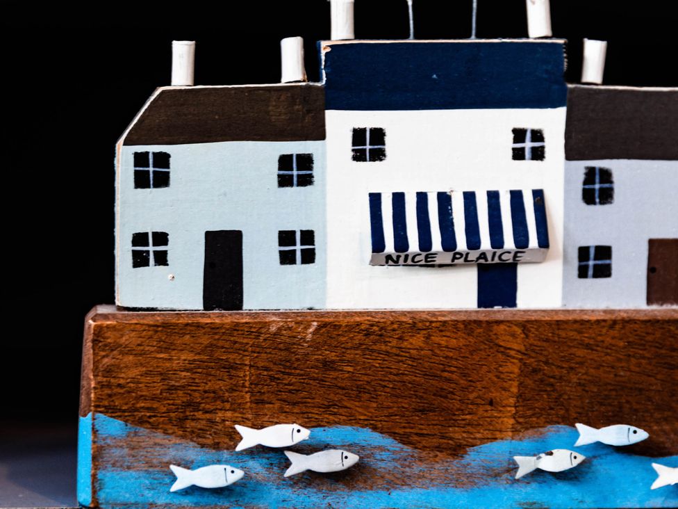 A wooden model of a house with a shop front and fish at Nice Plaice