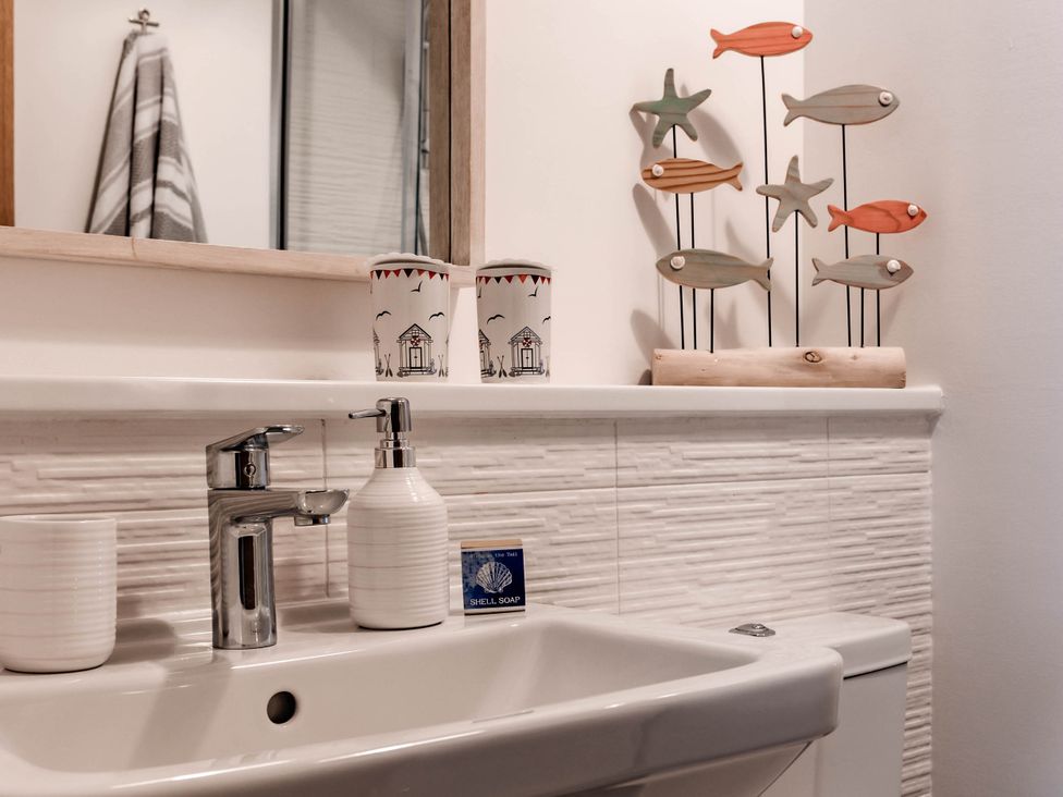 A bathroom with a sink, toilet, mirror, and decorative items at 