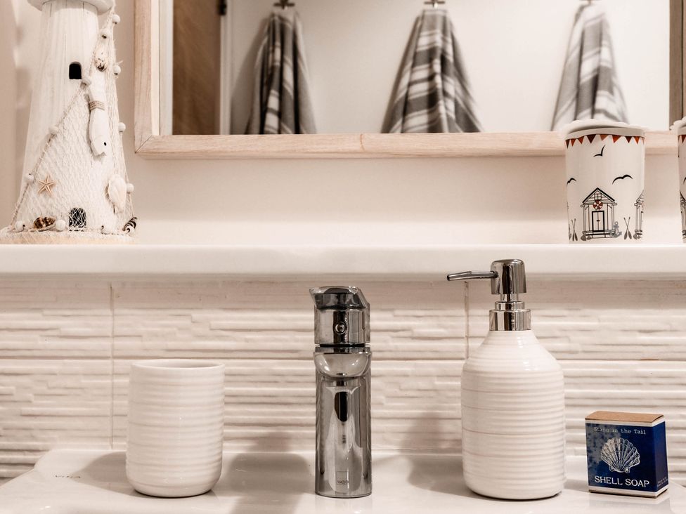 A bathroom with a soap dispenser and lighthouse decor at a coastal retreat