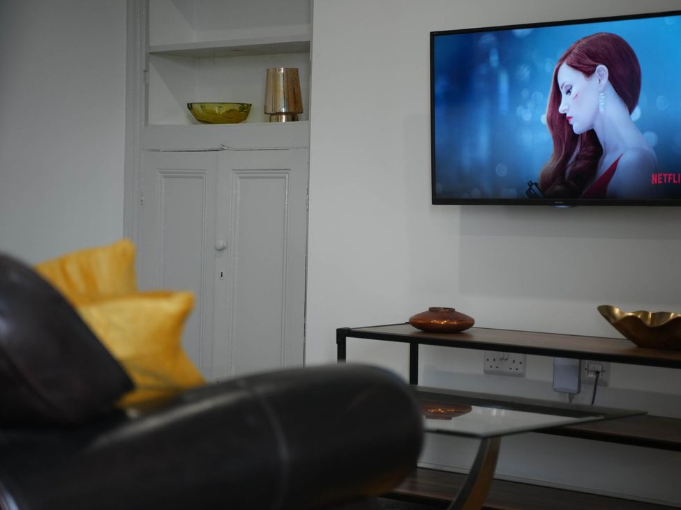 A living room with a television and decorative items at The Old Barn in Manchester