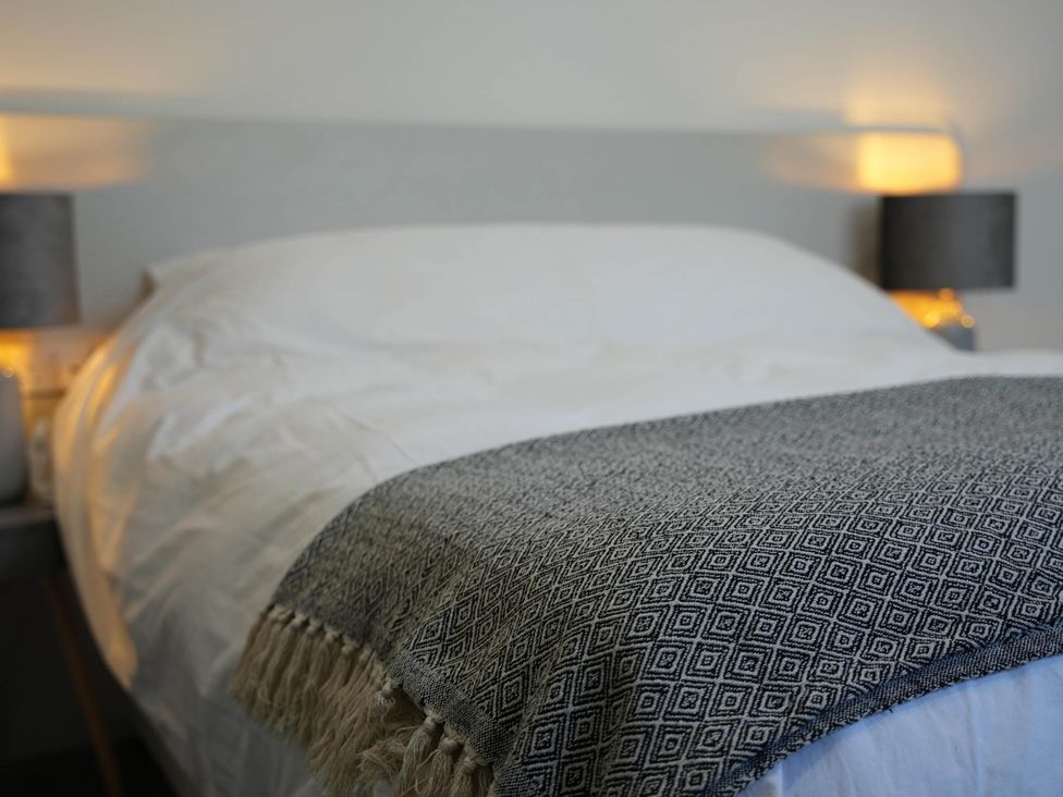 A bed with a patterned blanket and bedside lamps in a bedroom