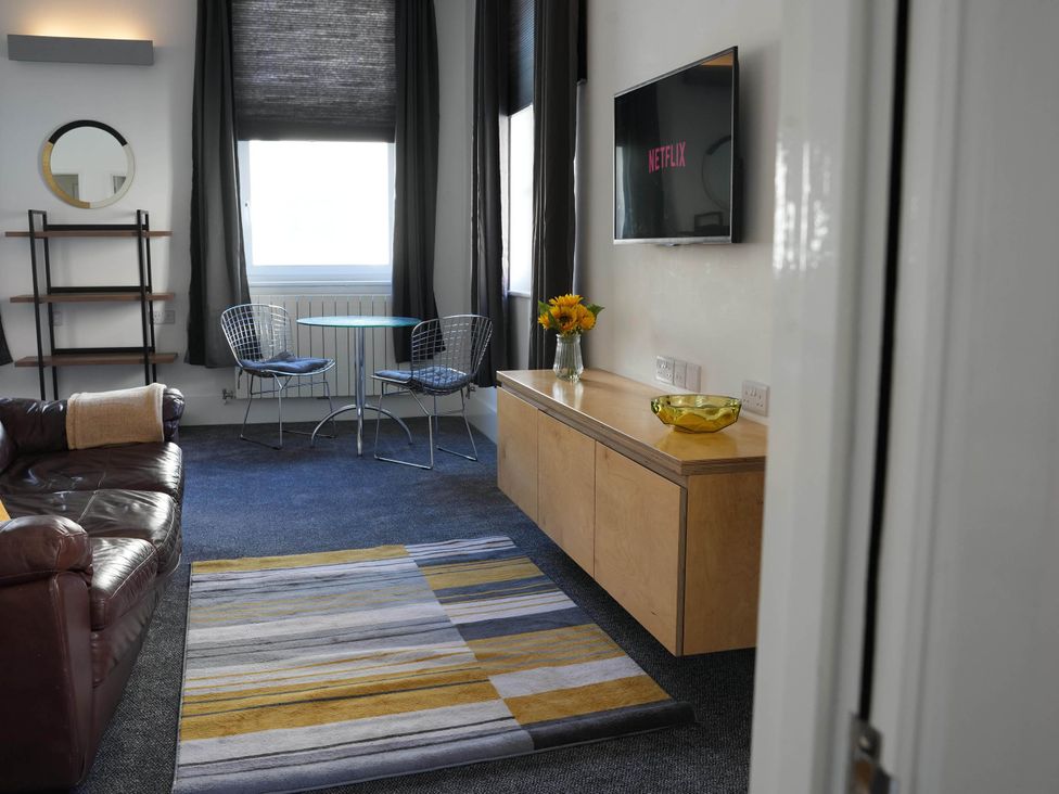 A living room with a sofa, TV and dining table at the property