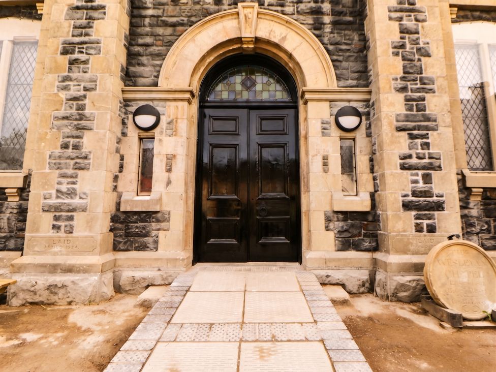 An entrance with a black door and stone walls at Capel Llani in Llanidloes