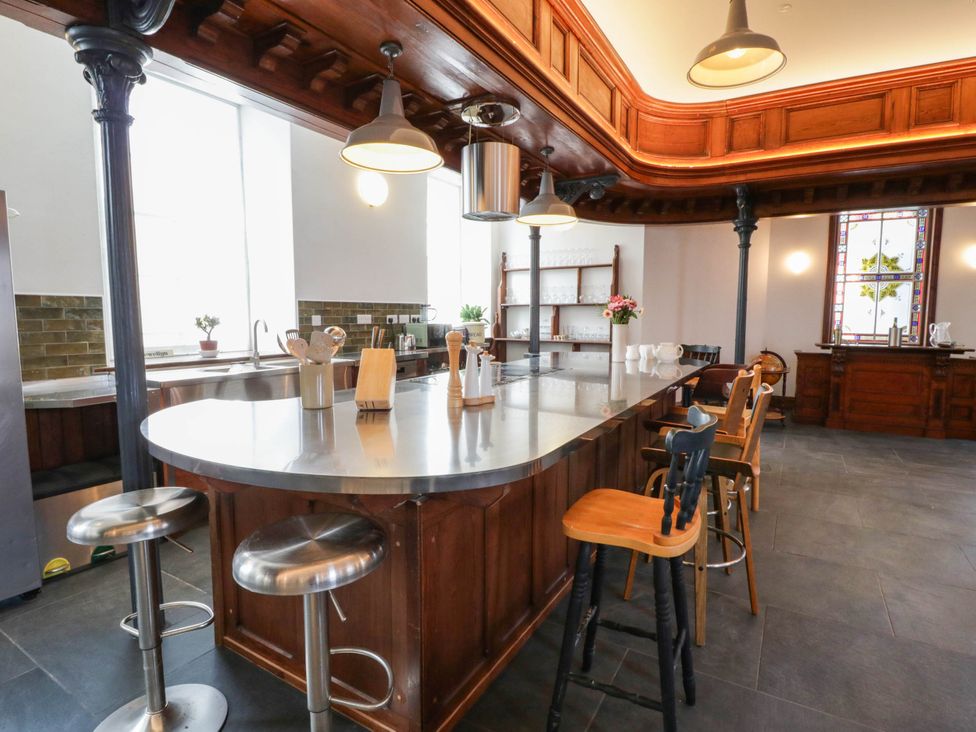 A kitchen with an island and stools at Capel Llani in Llanidloes