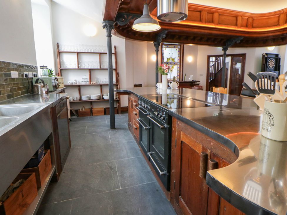 A kitchen with stove, sink and shelves at Capel Llani in Llanidloes