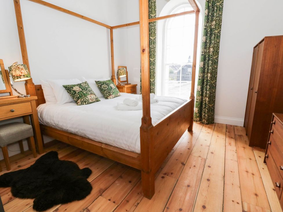 A bedroom with a four-poster bed and wooden furniture at Capel Llani in Llanidloes