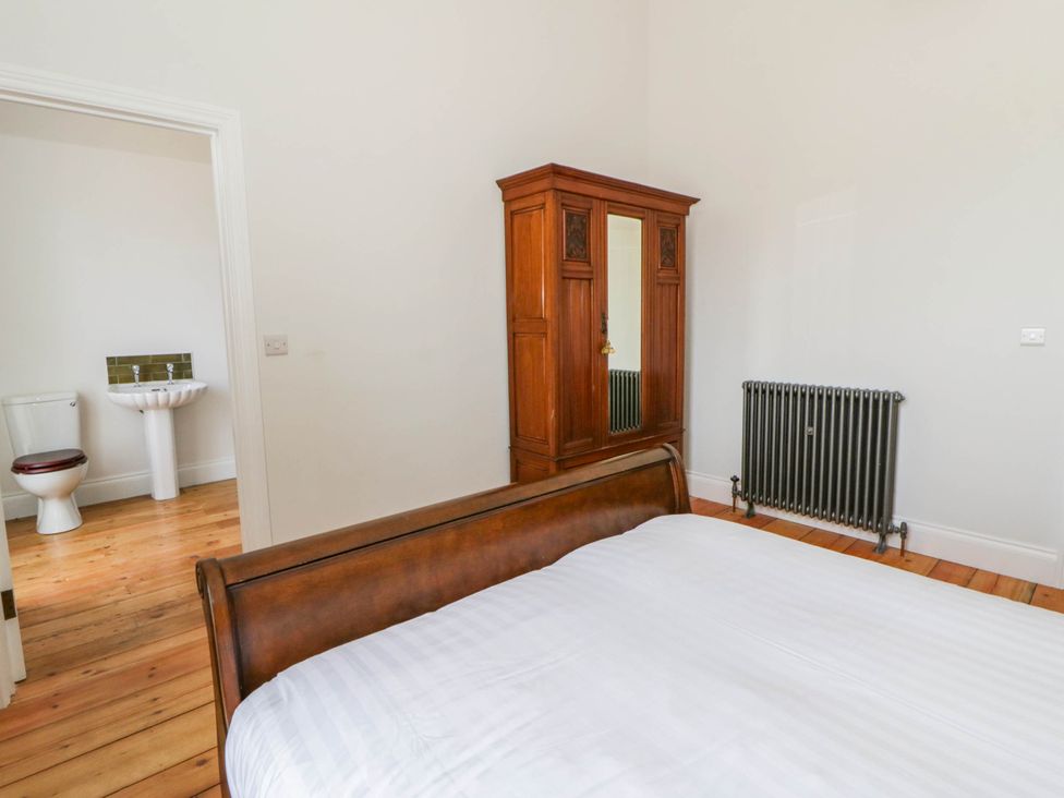 A bedroom with a bed and wardrobe with an adjacent bathroom at Capel Llani in Llanidloes