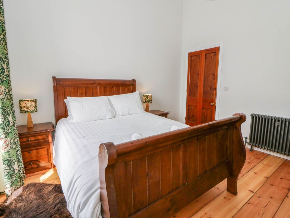 A bedroom with a wooden bed and side tables at Capel Llani Llanidloes