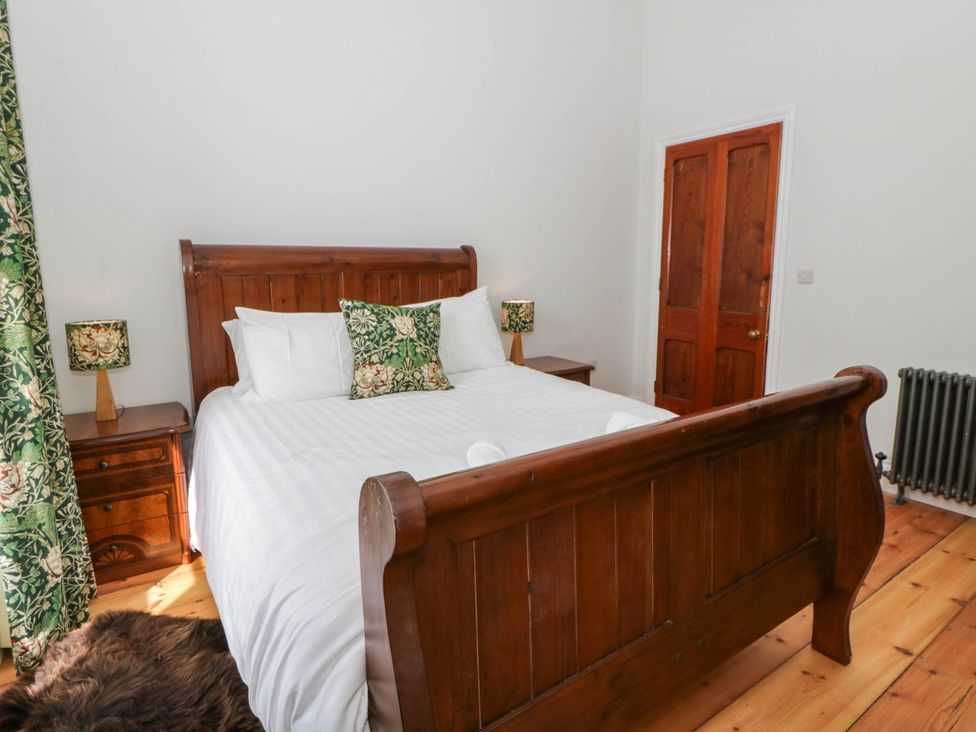 A bedroom with a wooden bed and bedside tables at Capel Llani in Llanidloes