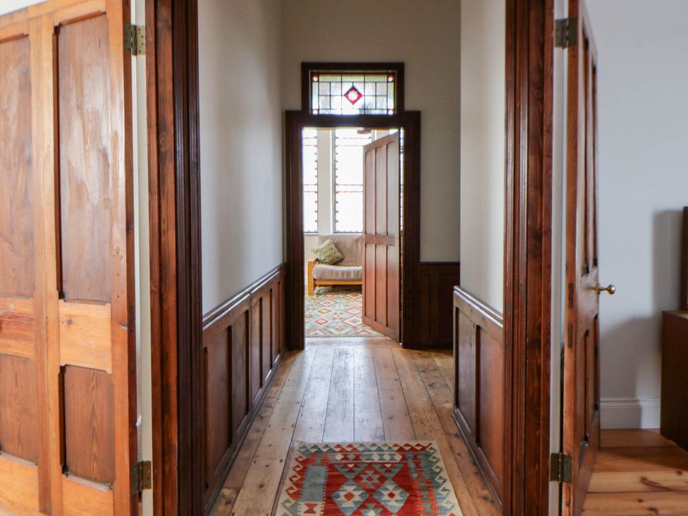 A hallway with wooden doors and a rug at Capel Llani in Llanidloes