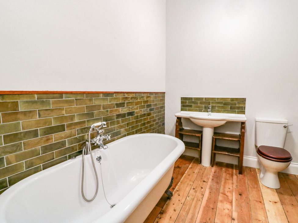 A bathroom with a bathtub, sink, and toilet at Capel Llani in Llanidloes