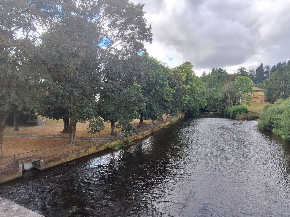 A river with trees and a path beside it at Capel Llani in Llanidloes