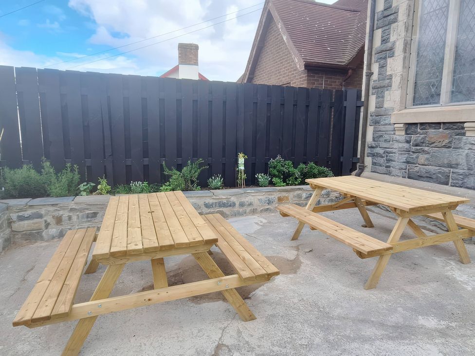 An outdoor area with wooden tables and decorative plants at Capel Llani Llanidloes