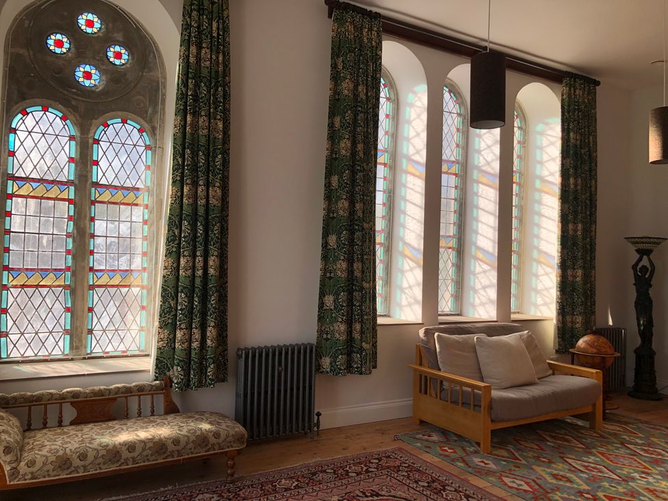 A living room with stained glass windows and a sofa at Capel Llani in Llanidloes