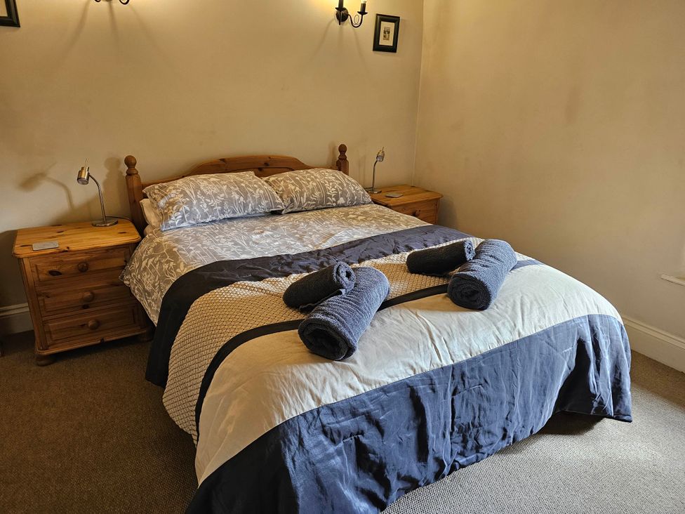 A bedroom with a bed, bedside tables, and towels in a property