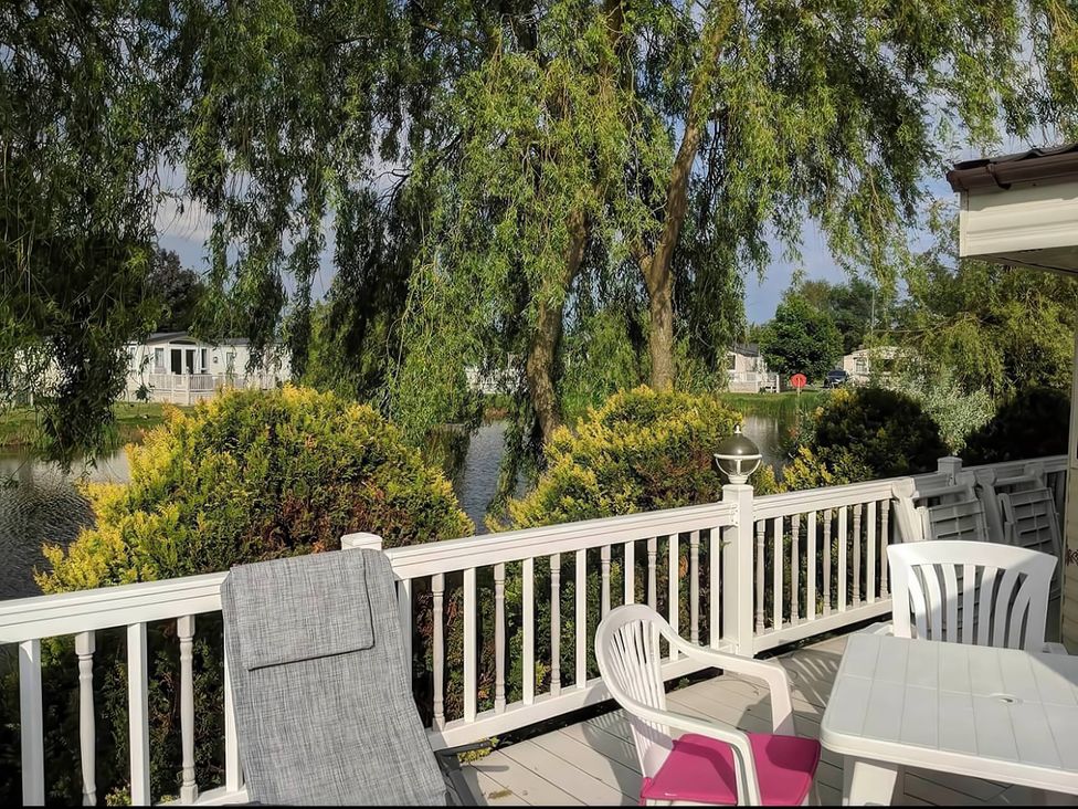 An outdoor deck with chairs and a table overlooking a body of water at an unspecified location