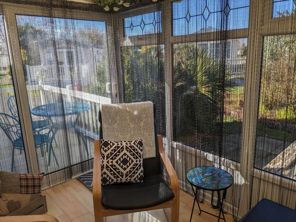A conservatory with a chair and a small table at The Old Barn in Manchester