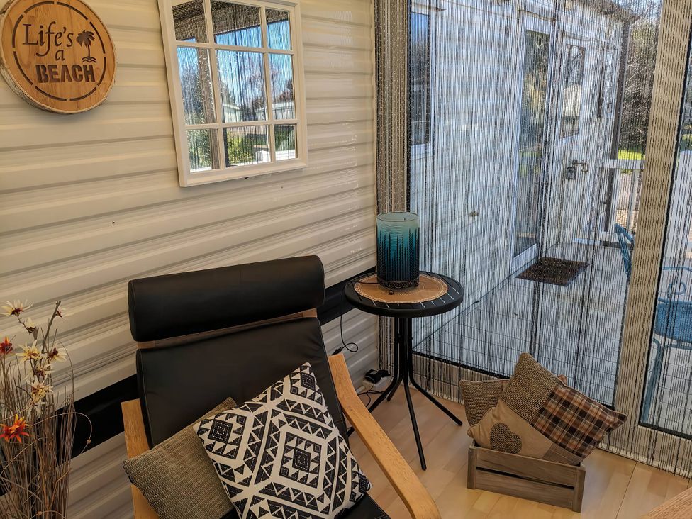 A sunroom with a chair, table, and decorative items at The Beach House in an unspecified location