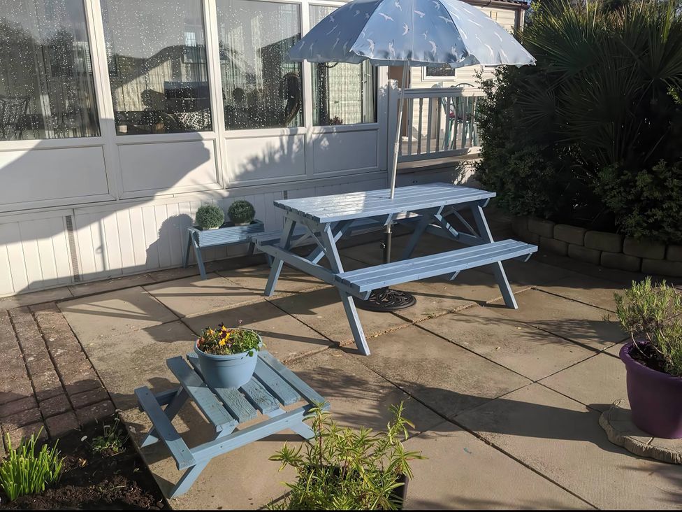 A garden with a table, benches, and an umbrella at the property in 