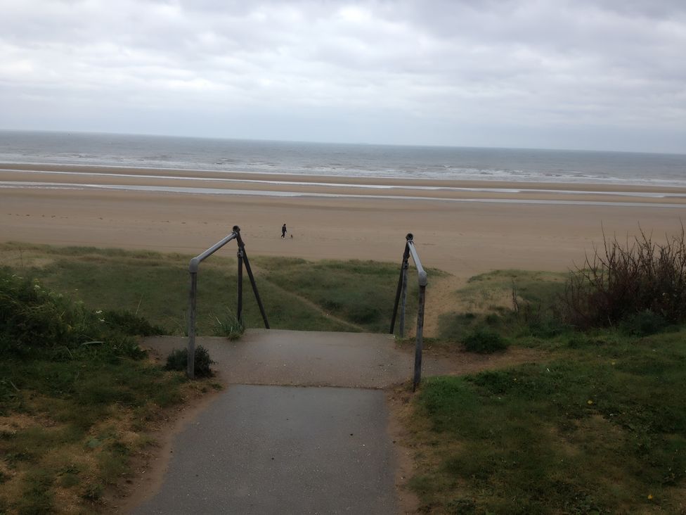 Steps leading down to a beach with a person walking at Ivy Corner 
