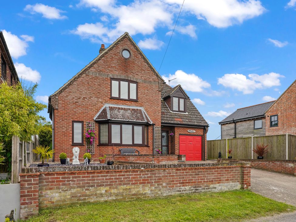 A house with a red door and garden at the property in an outdoor setting