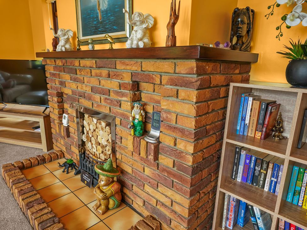 A living room with a brick fireplace, a bookshelf, and a television at the property in location