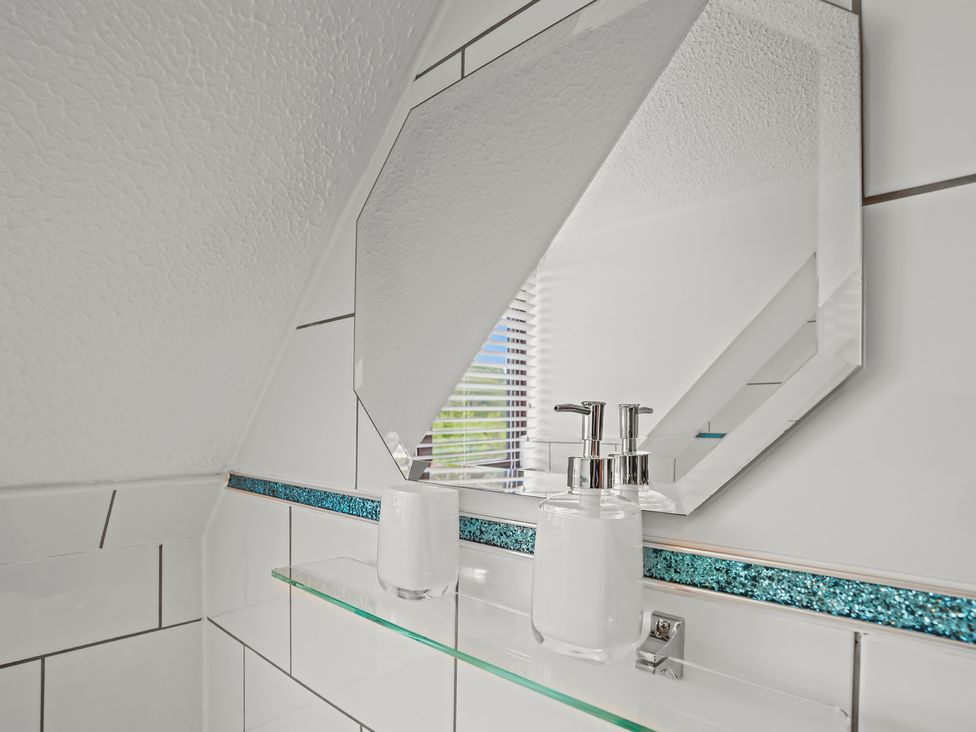 A bathroom with a mirror and soap dispenser on a shelf.