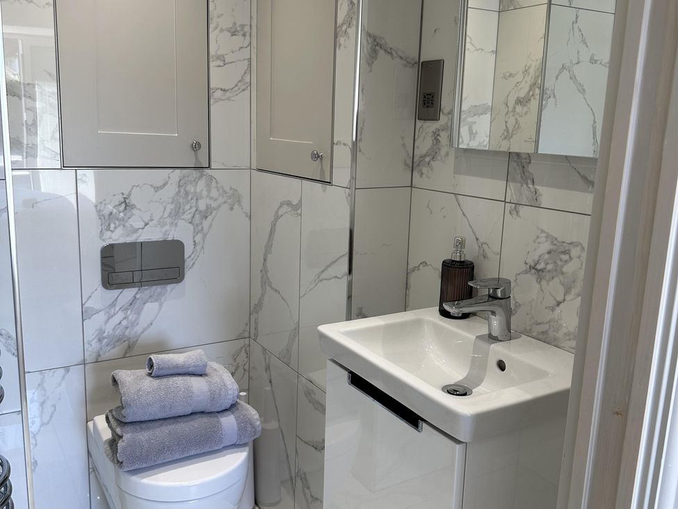 A bathroom with a toilet, hand wash basin, towels, and mirror at Quay house studio