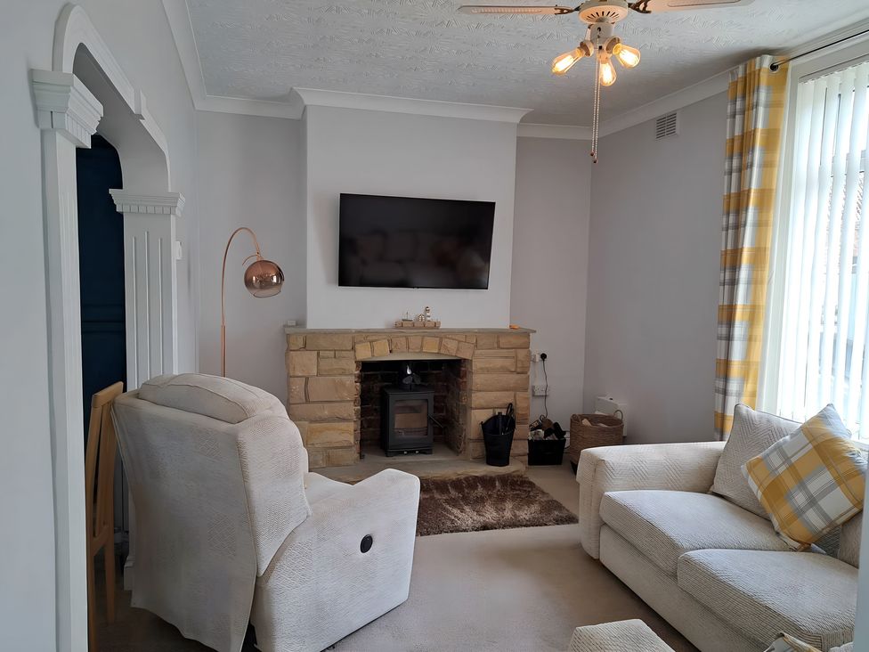 A living room with an armchair and a television at Fisherman's Cottage