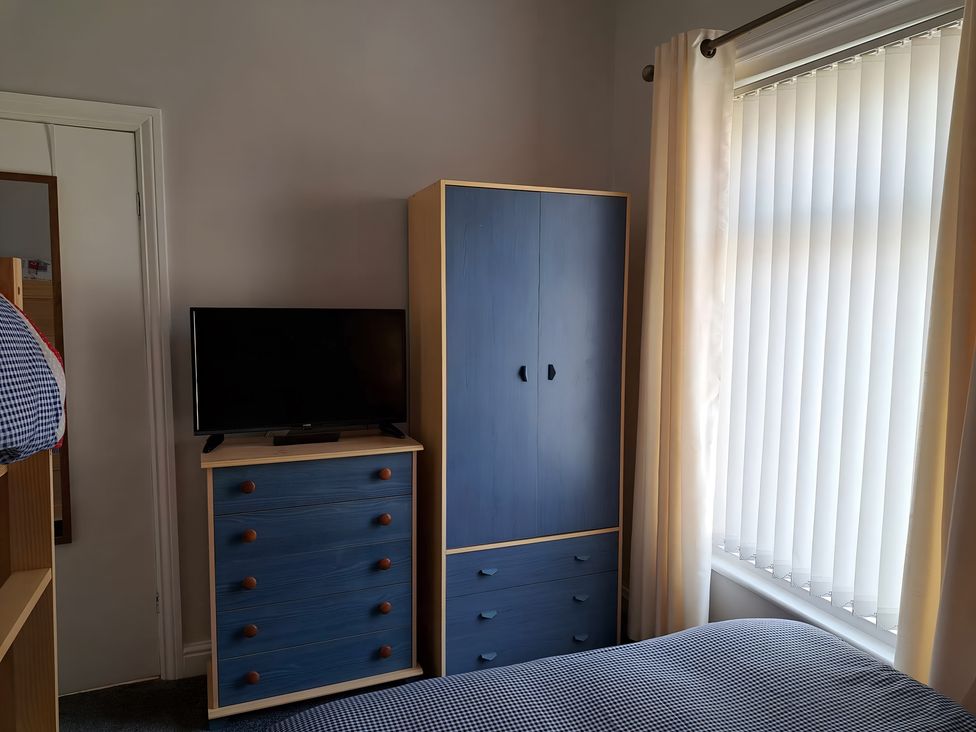 A bedroom with a television and wardrobe at Fisherman's Cottage