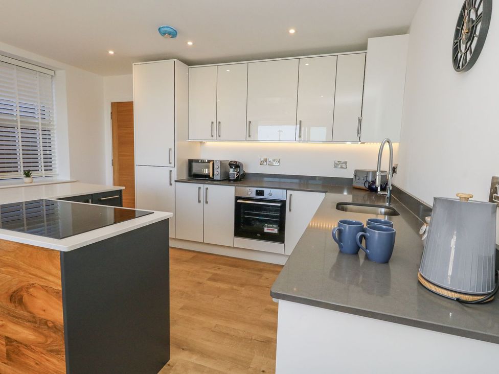 A kitchen with cabinets, a microwave, kettle, and mugs at Sea Fern House - 36 Poole