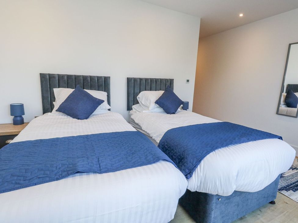 A bedroom with two beds and a bedside table at Sea Fern House - 36 Poole