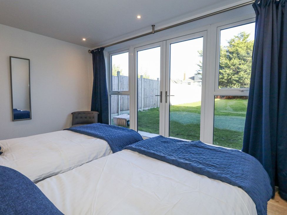 A bedroom with two beds and sliding doors at Sea Fern House - 36 Poole