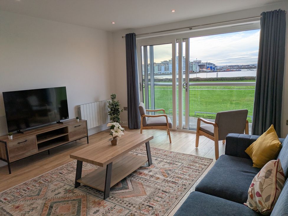 A living room with a television and furniture at Sea Fern House - 36, Poole