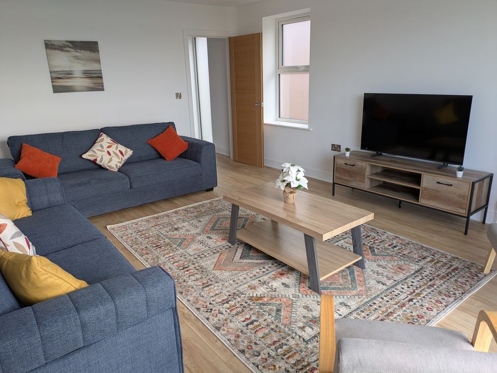 A living room with a coffee table, sofas, and a television at Sea Fern House - 36 in Poole