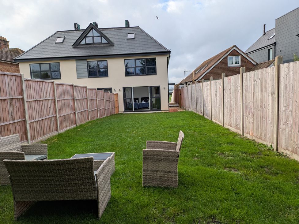 A garden with grass and chairs at Sea Fern House - 36 in Poole