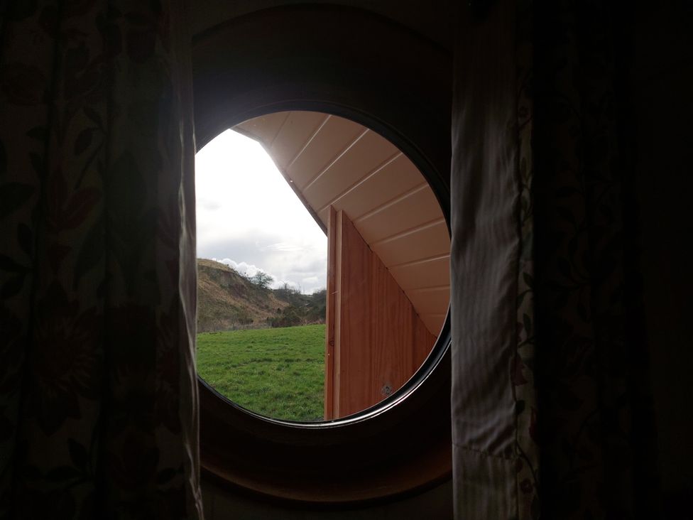 A window view overlooking grassland and hills at the property in 
