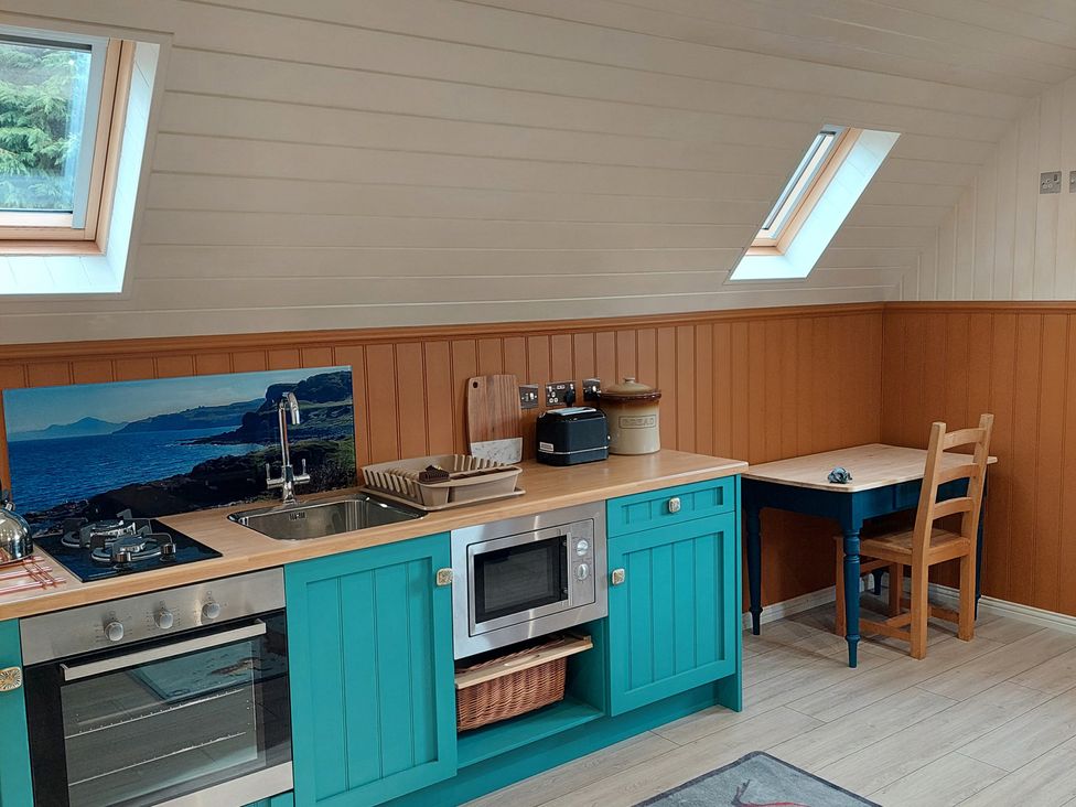 A kitchen with a stove, sink, microwave, and table at The Old Barn in Manchester