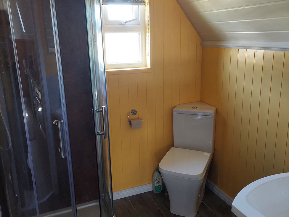 A bathroom with a shower, toilet, and sink with yellow walls at the property