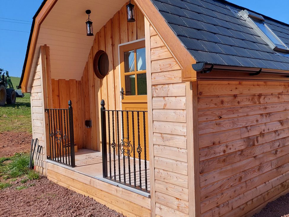 A cabin exterior with wood siding and a railing at 