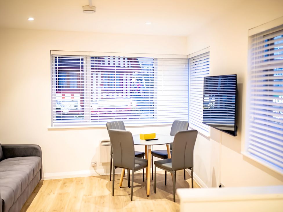 A living room with a dining table and television at Red Rose Apartment